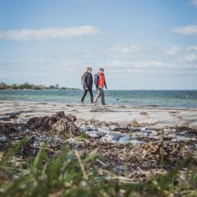 Mænd vandrer ved strand